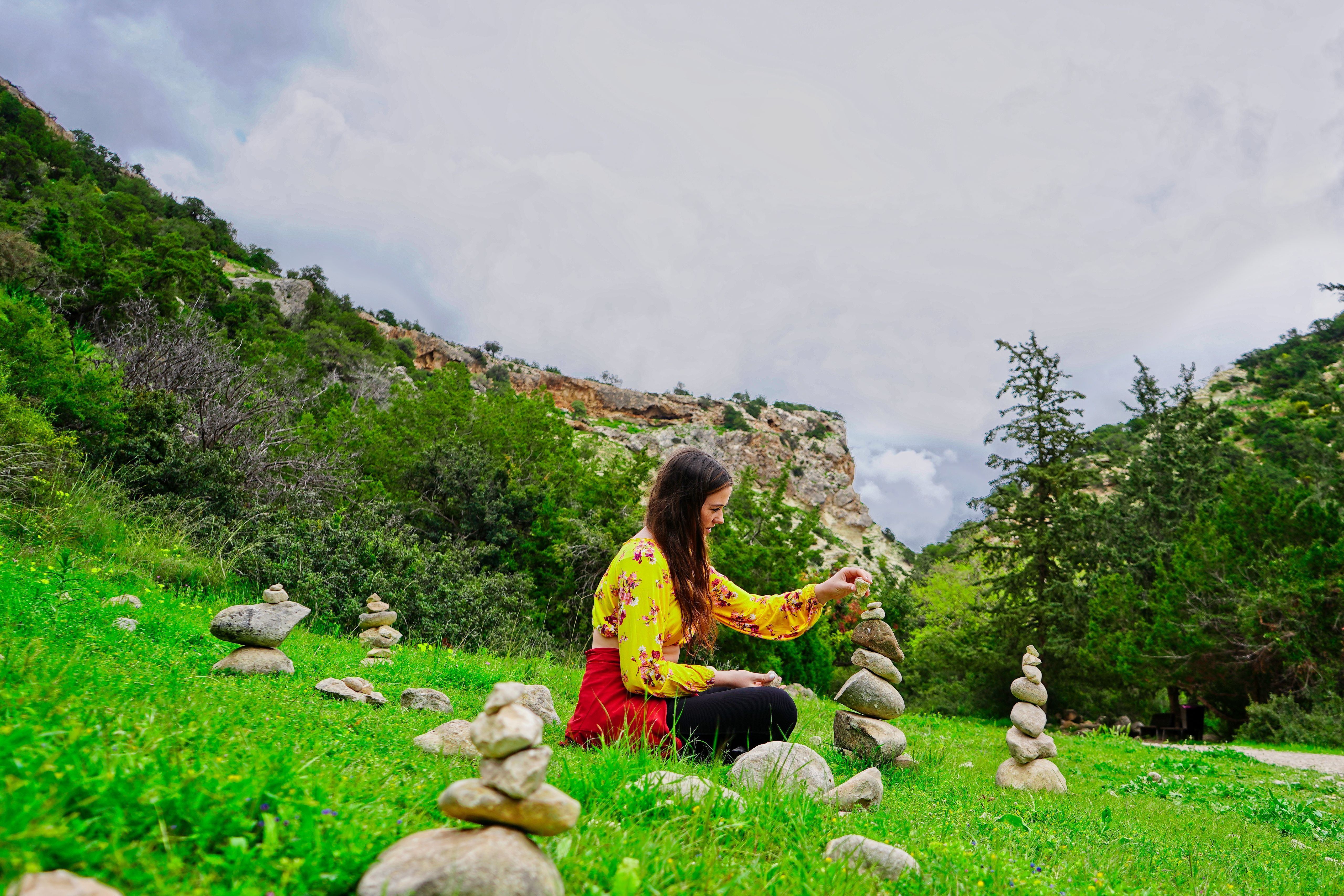 Calm female putting rock on top of each other in nature in daylight ...