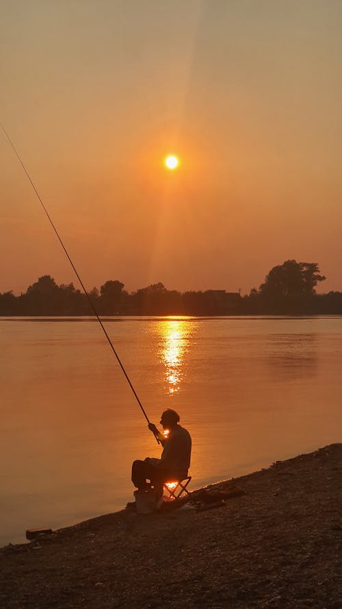 Silhouetted of a Man Fishing on the Shore
