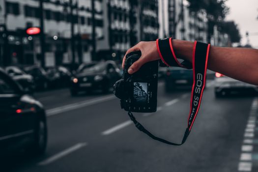 A photographer captures street scenes with a DSLR on a bustling road.