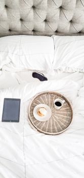 Relaxing morning in bed with coffee, croissant, and ebook on tablet. Perfect for cozy mornings.