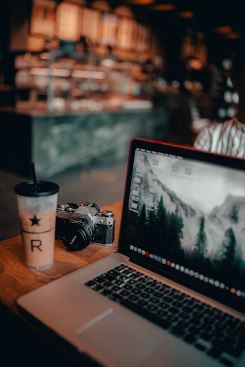 Computer Portatile E Fotocamera Sul Tavolo Con Un Bicchiere Di Caffè