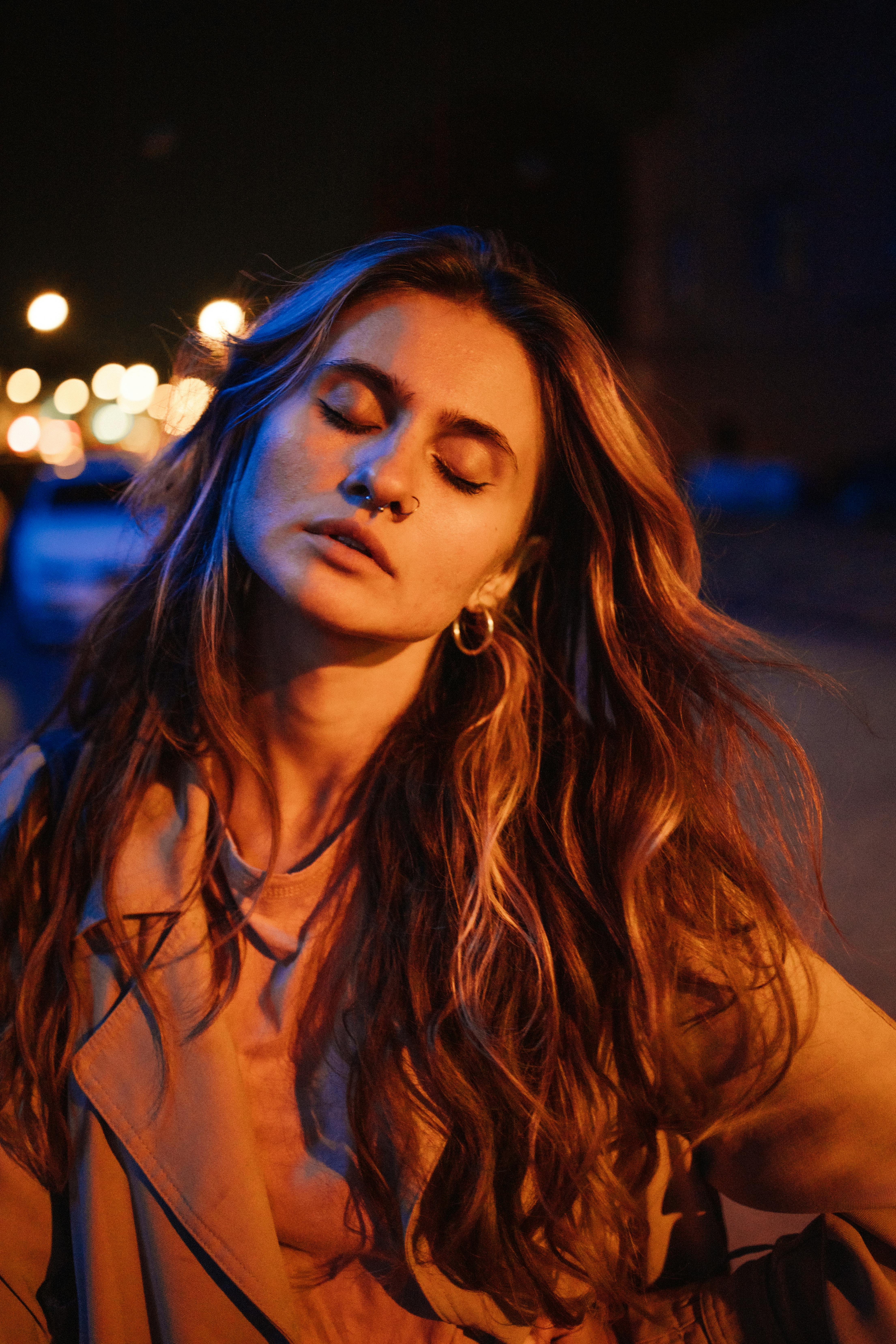 一个女人闭着眼睛，飘逸的长发和耳环的艺术夜间肖像