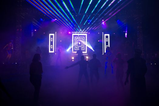 在充满活力的夜总会里，剪影般的人群随着彩色激光灯和烟雾效果起舞