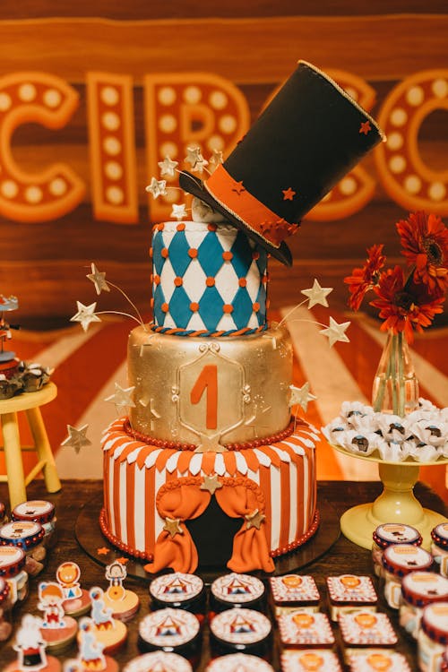 Colorful tiered cake near desserts on table for circus festival against colorful background