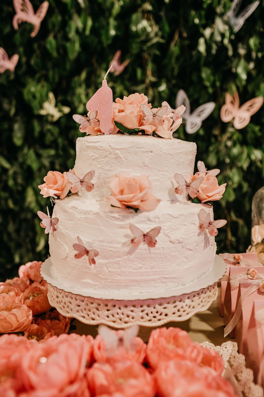 A tiered pink cake decorated with flowers and butterflies