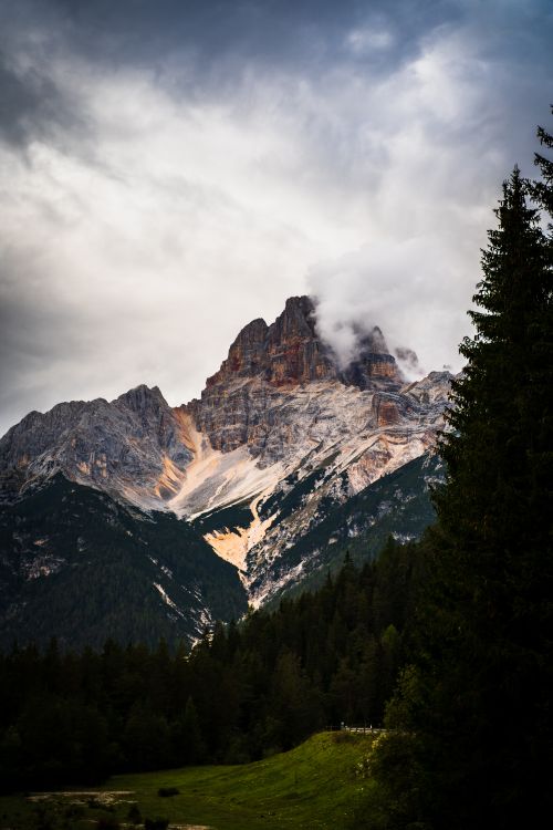 Free Stunning view of a mountain peak surrounded by trees and clouds in the Dolomites, Italy. Stock Photo