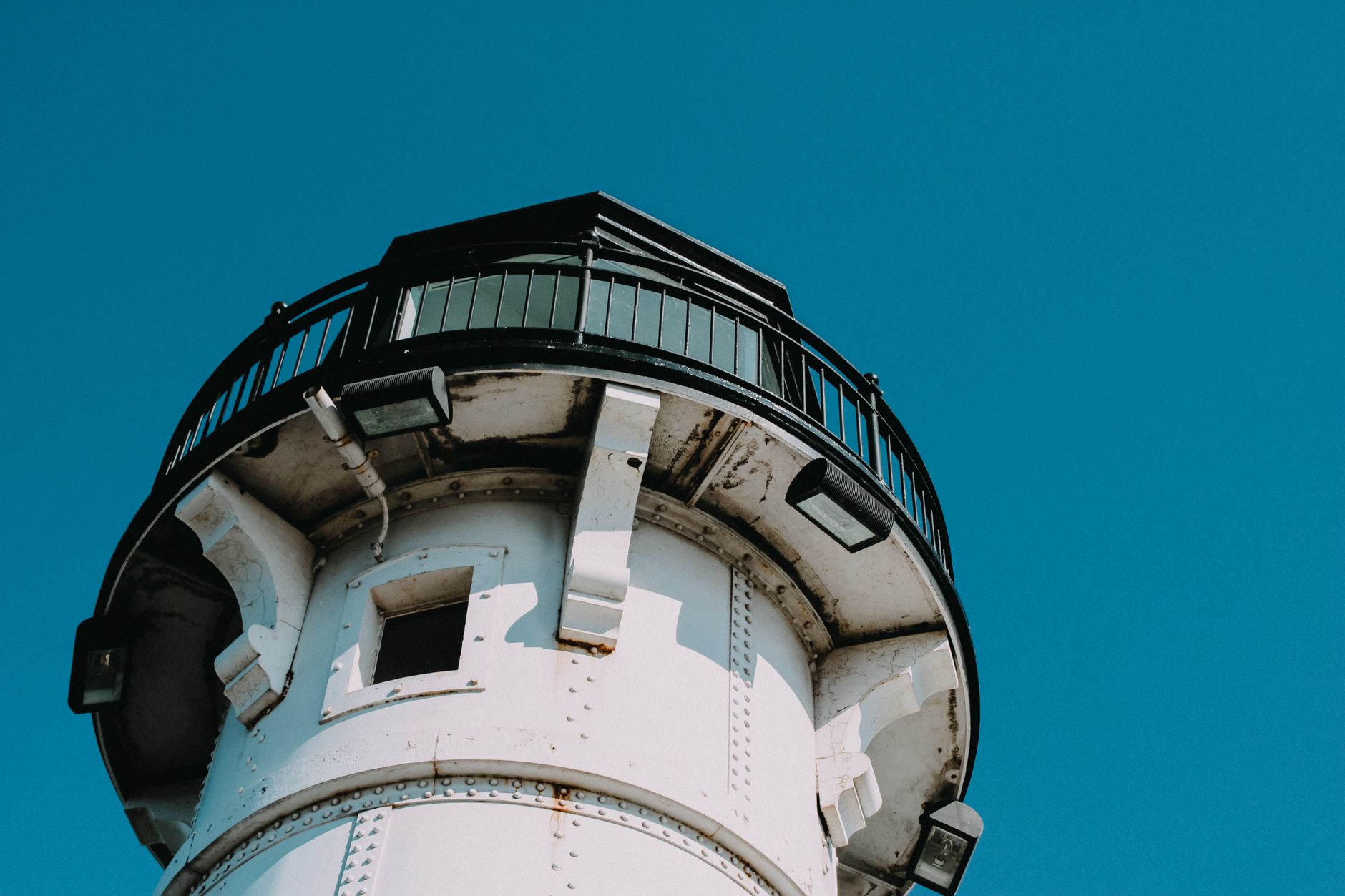 Close-up of a lighthouse in Duluth, MN with a vibrant blue sky backdrop.