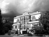 这是一座经典公寓楼的黑白照片，头顶上云层显得格外戏剧性