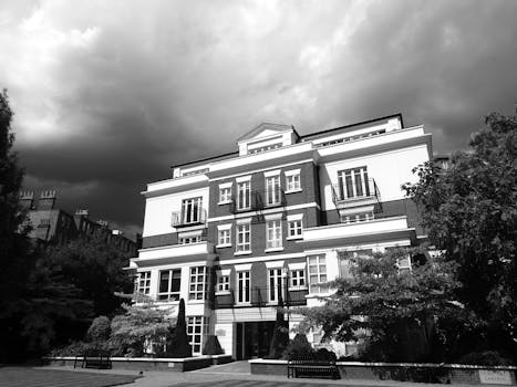 这是一座经典公寓楼的黑白照片，头顶上云层显得格外戏剧性