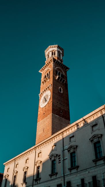 Historic Torre dei Lamberti clock tower in Verona, Italy against clear blue sky. Iconic landmark in Veneto region.