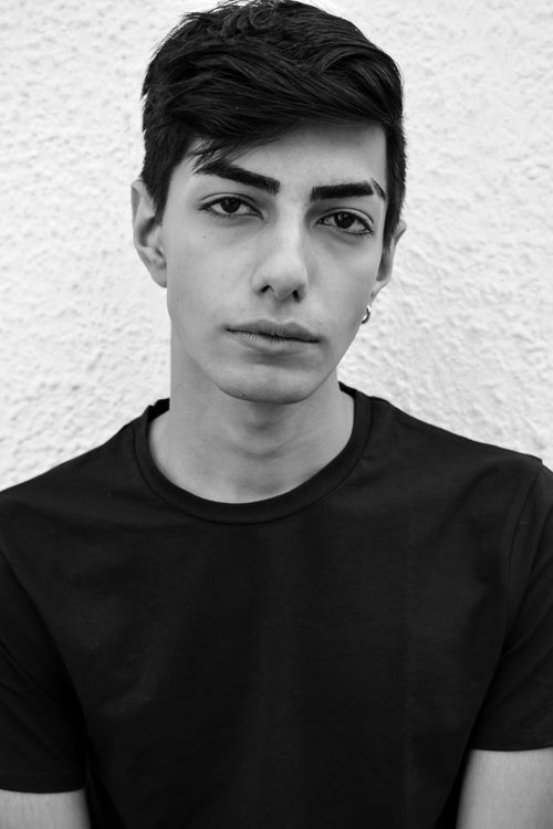 Free Classic black and white portrait of a young man in a black shirt, posing confidently. Stock Photo