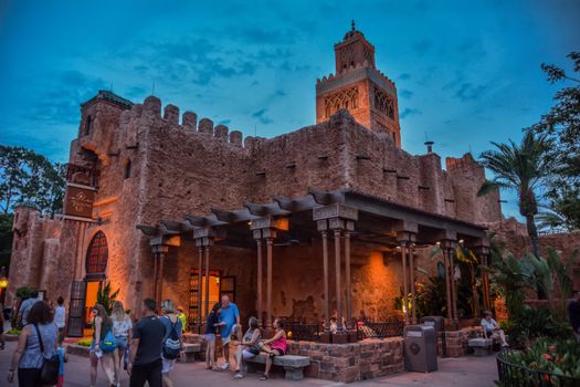 Tourists enjoy the evening at a Moroccan styled building, beautifully lit at dusk.