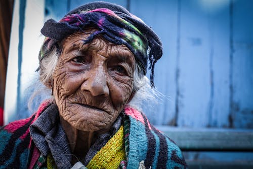 Free Senior wrinkly ethnic woman in headscarf near shabby building Stock Photo