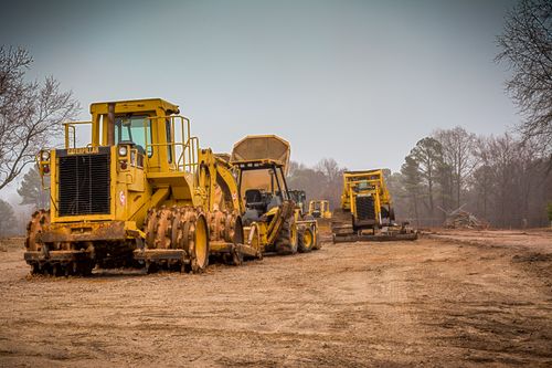 Free Yellow construction vehicles at a worksite in Raleigh, NC on a cloudy day. Stock Photo