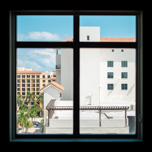 Free View Of White Concrete Building From A Glass Window Stock Photo