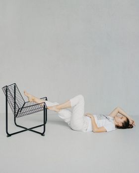 Artistic minimalist photo of a woman relaxing indoors on the floor with a unique chair.