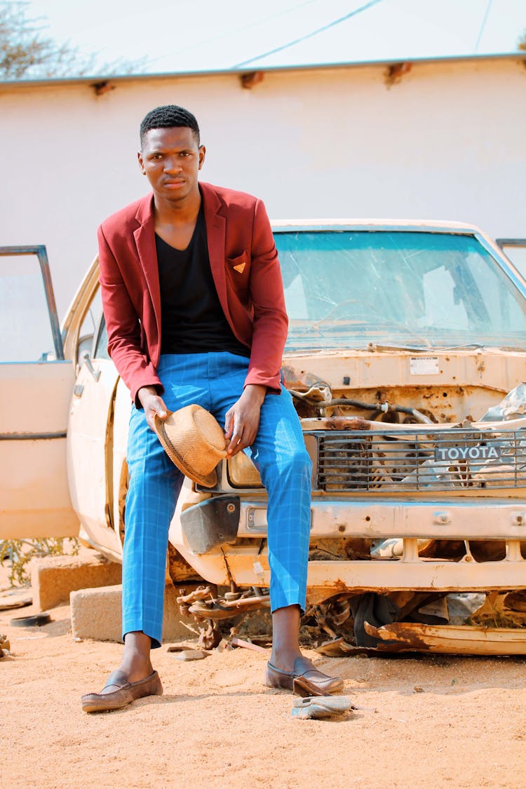 Confident Young Black Guy Leaning On Damaged Old Car