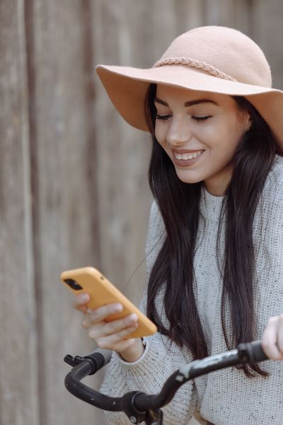 Woman smiling at her phone outdoors, photo by Thirdman on Pexels
