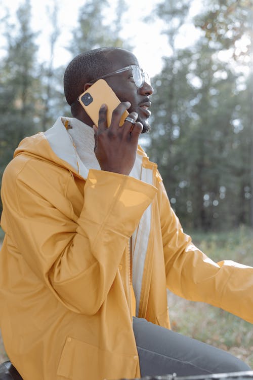 Photos gratuites de Homme en veste jaune, à l'aide d'un Iphone