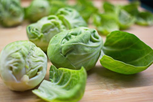 Closeup of ripe fresh Brussels sprouts with peels placed on wooden cutting board