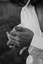 Black and white of crop anonymous brunet in white shirt shielding fire of lighter with hand while lightening cigarette in mouth