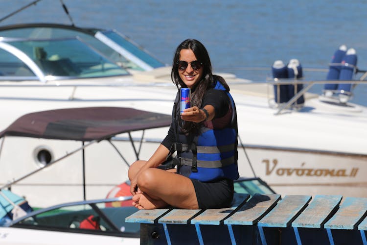 Woman Holding A Can Sitting On A Wooden Deck