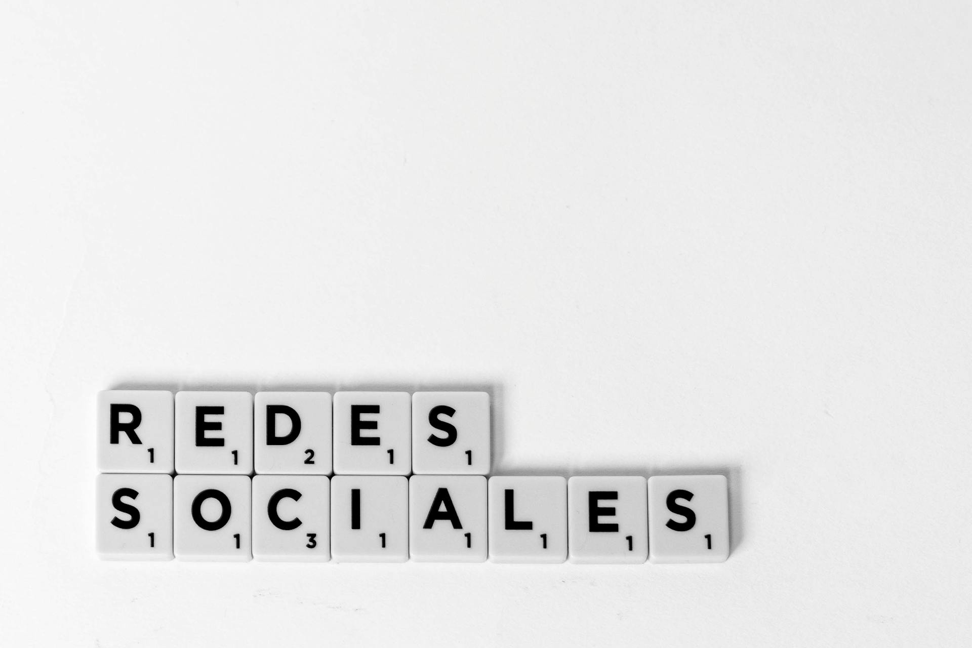 Scrabble tiles spelling 'Redes Sociales' illustrating a social media concept on a white background.