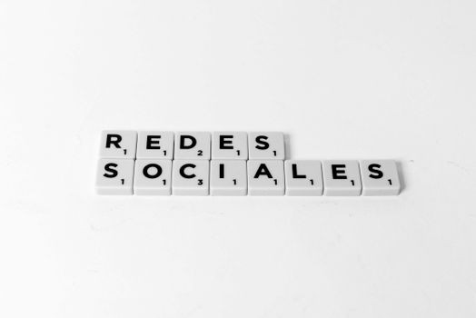 Scrabble tiles form 'Redes Sociales' on a white background, symbolizing social networks.