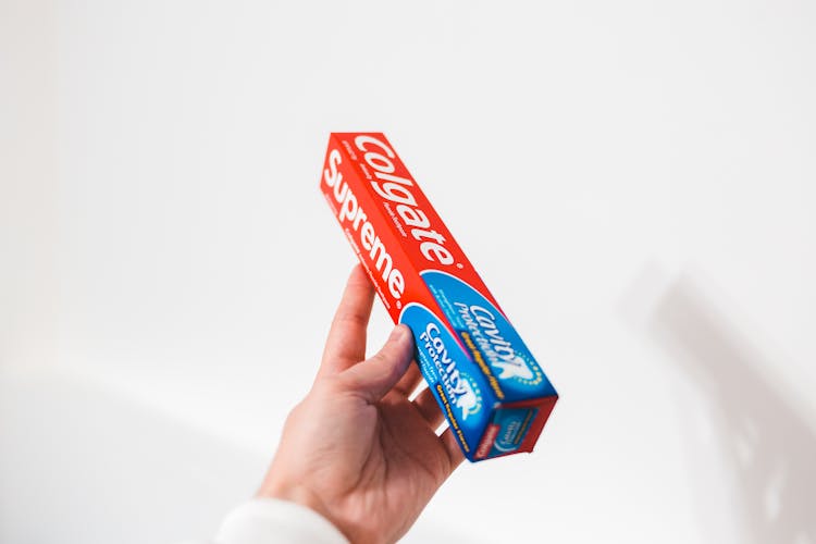 A Person Holding Colgate Toothpaste Box