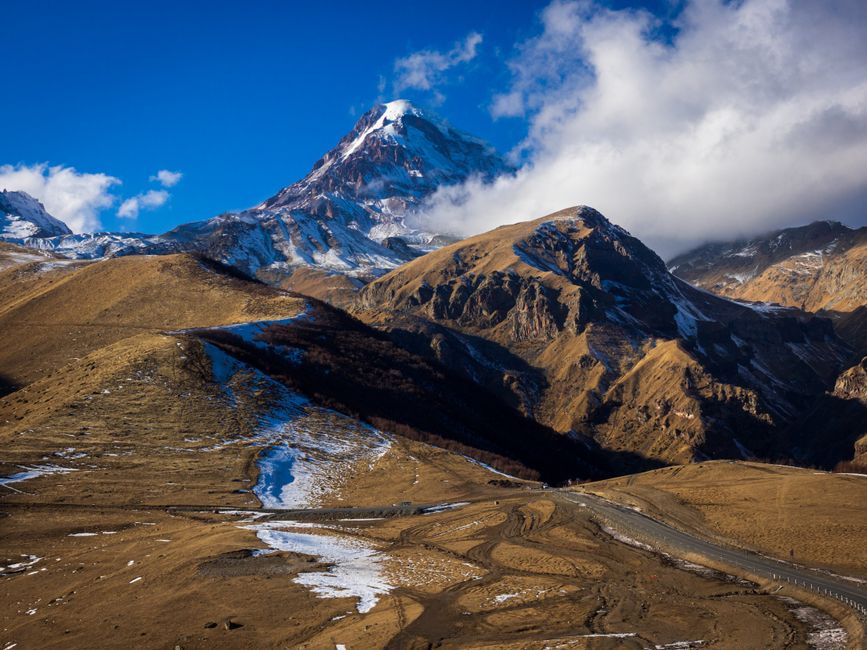 Explore the breathtaking landscape of Mount Kazbek with its snowcapped peaks and winding roads in Georgia.