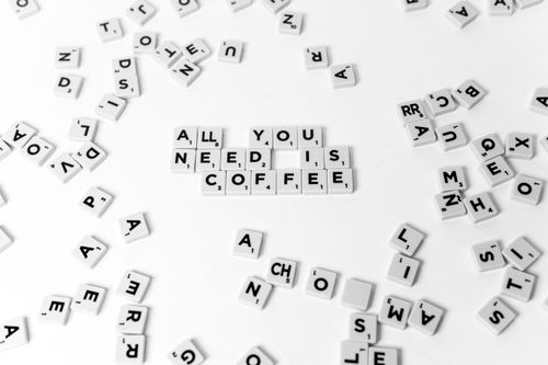 Free Scrabble tiles arranged to say 'All You Need is Coffee' on a white background. Stock Photo
