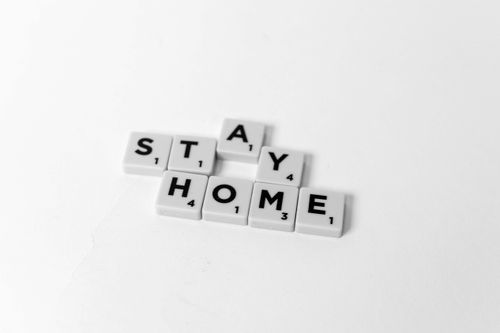 Free Scrabble tiles arranged to spell 'Stay Home' on a white background, conveying a preventive message. Stock Photo