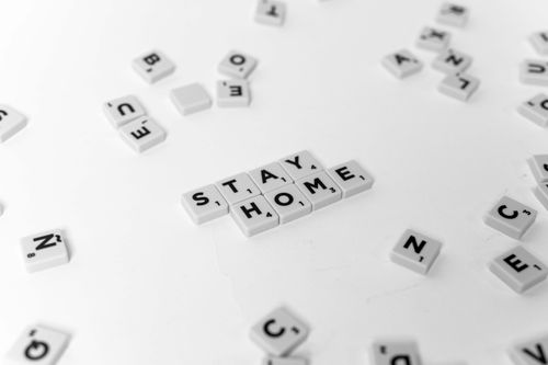 Free Scrabble tiles arranged to spell 'Stay Home' on a white background, conveying a stay-at-home message. Stock Photo