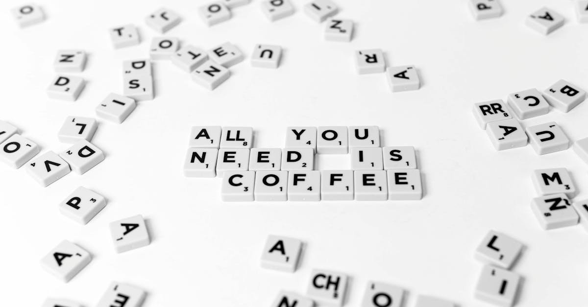 Scrabble tiles spell out 'All You Need Is Coffee' on a white background, offering a creative still life.