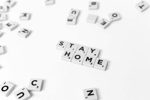 Free Scrabble tiles spelling 'Stay Home' on a white background, emphasizing the pandemic message. Stock Photo