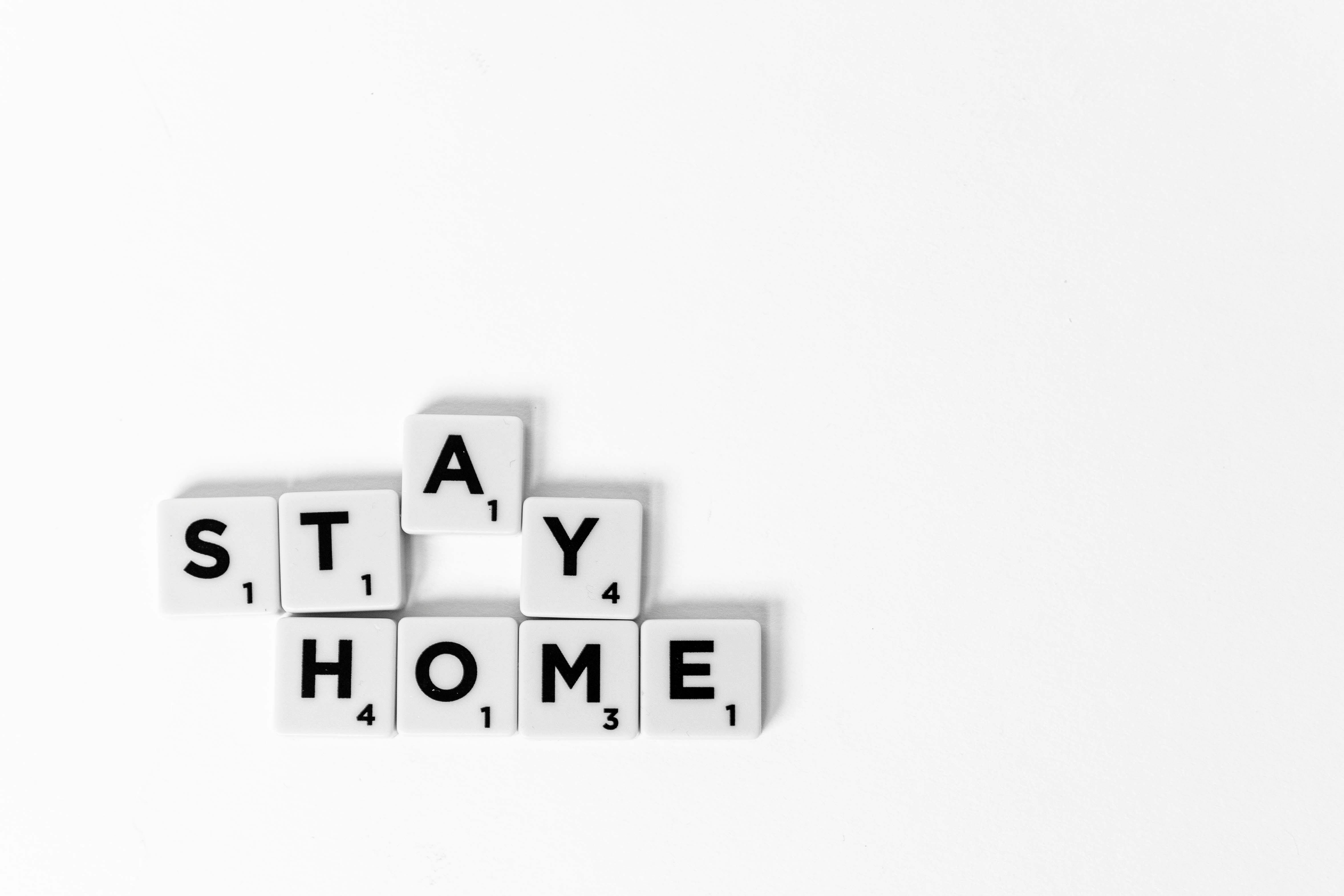 A conceptual image with the message "Stay Home" spelled out using Scrabble tiles on a white background.