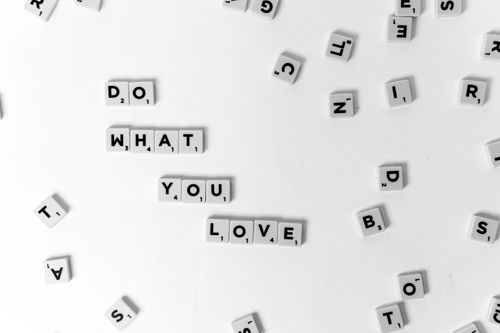 Free Scrabble tiles spell 'Do What You Love' on a white background. Stock Photo
