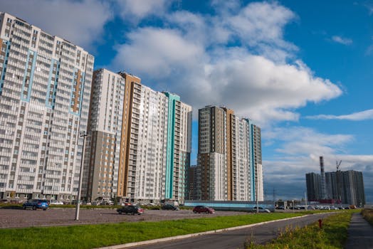 Contemporary high-rise buildings captured against a bright blue sky with scattered clouds.