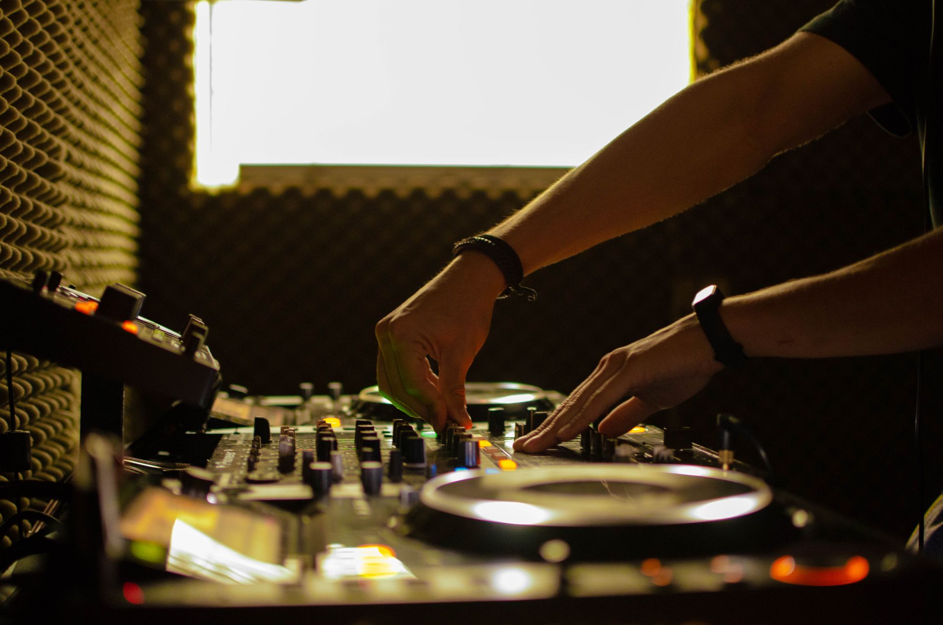 DJ using turntables and a mixer with acoustic panels indoors.