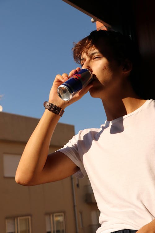 A Man in White Crew Neck T-shirt Drinking from Can