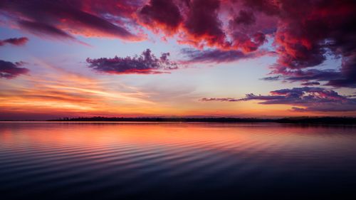 Free A stunning sunset paints the horizon with vibrant colors over calm ocean waters. Stock Photo
