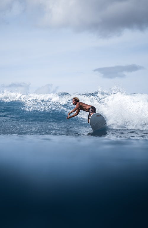 Energetic black man surfing board on foamy sea waves