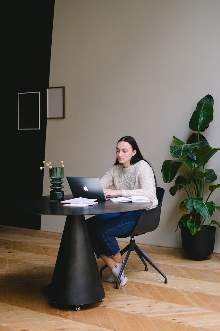 Business Woman In White Sweater Sitting On Chair Using Macbook