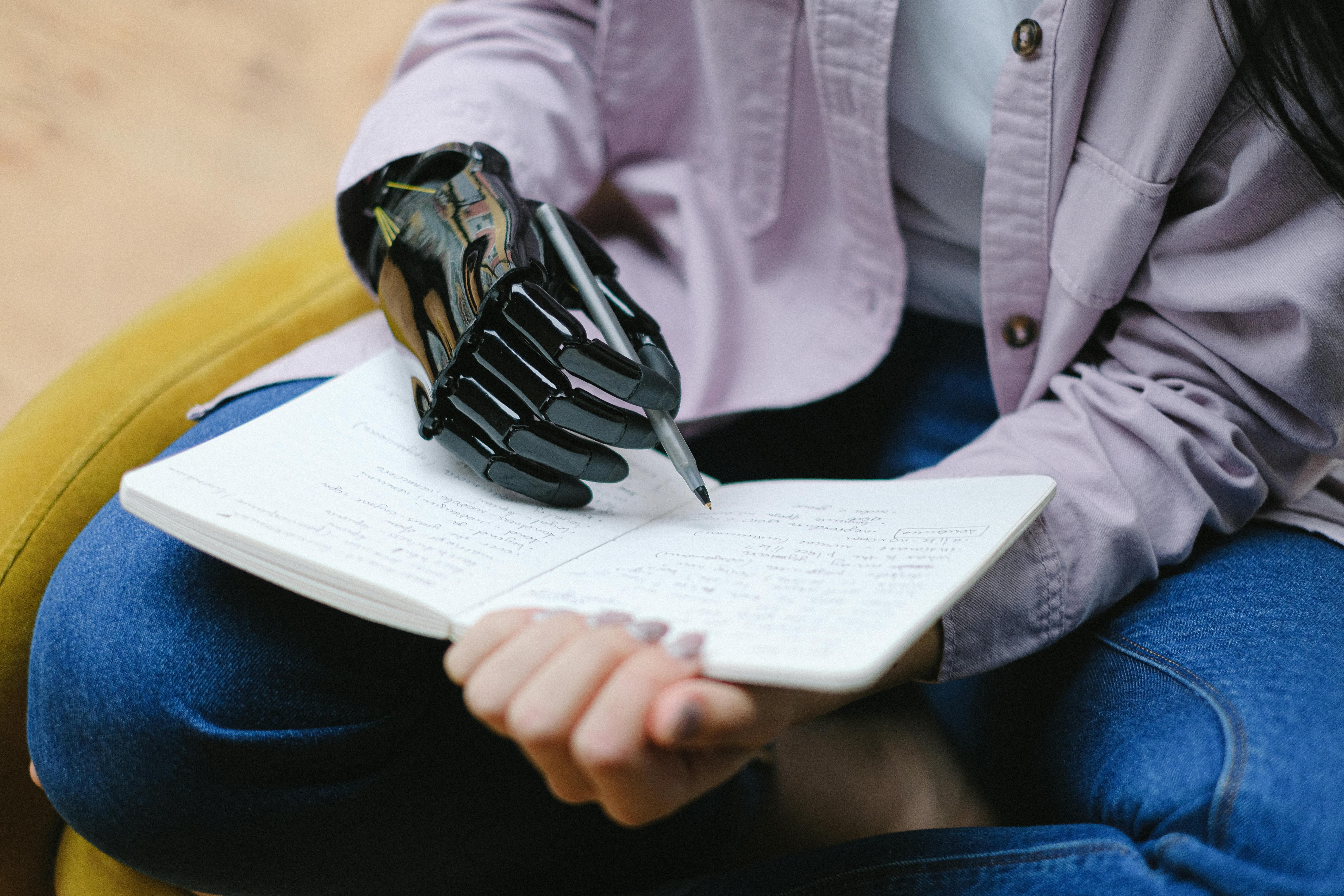 woman with modern prosthesis of hand writing in notebook