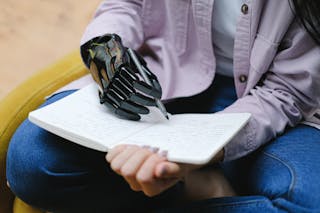 Woman with modern prosthesis of hand writing in notebook