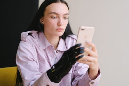 Free Adult woman with bionic arm using smartphone indoors, representing innovation and technology. Stock Photo