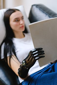 一名戴着仿生假肢的女性在室内一边放松一边读书，重点介绍了技术与生活方式