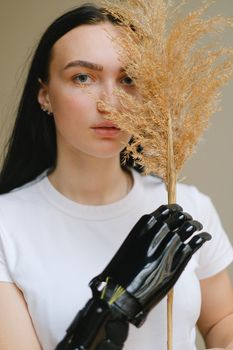 Portrait of a woman with a prosthetic arm holding dried pampas grass indoors.