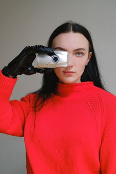 一名身穿红色毛衣的女子手持仿生假手相机