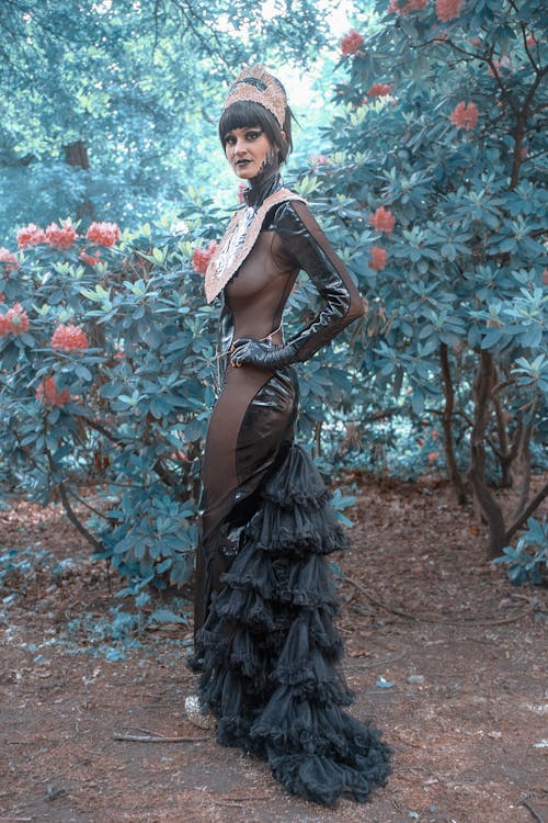 Femme En Robe Noire Et Marron Debout Près De Fleurs Rouges